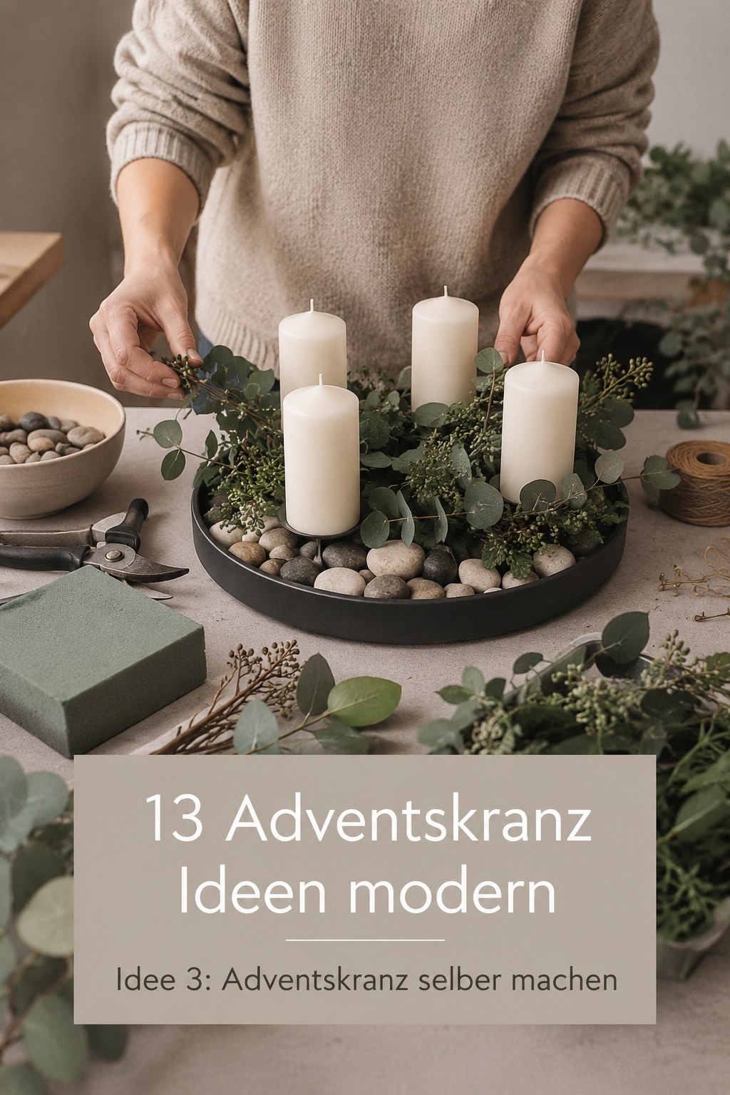 Hände arrangieren einen Adventskranz selber machen mit Eukalyptus, Kieselsteinen und weißen Kerzen