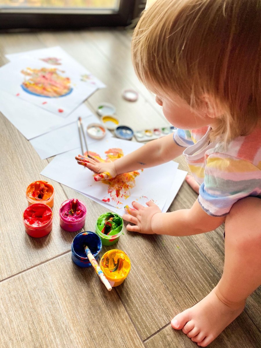 Kleinkind spielt kreativ mit Fingerfarben